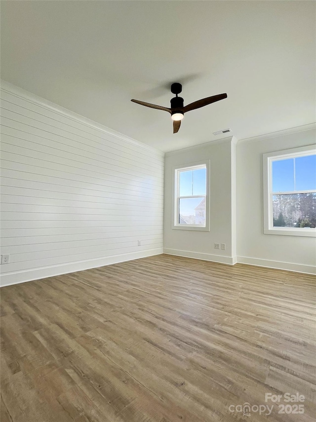 empty room with visible vents, ornamental molding, and wood finished floors