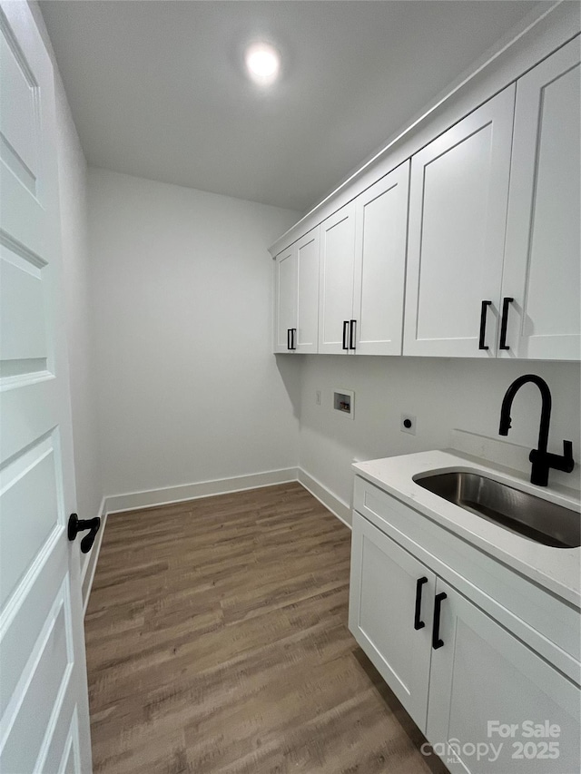 clothes washing area featuring hookup for a washing machine, a sink, electric dryer hookup, wood finished floors, and baseboards