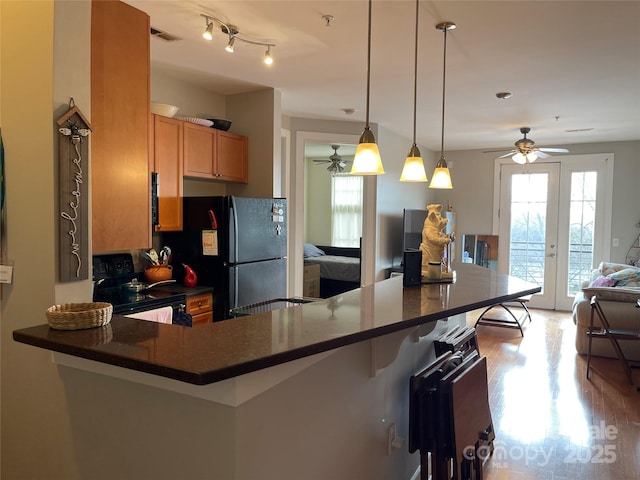 kitchen with dark countertops, visible vents, open floor plan, black appliances, and a kitchen bar