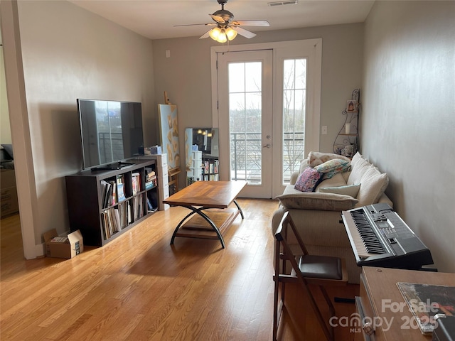 living room with a ceiling fan, french doors, visible vents, and wood finished floors