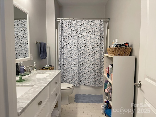 bathroom with double vanity, tile patterned flooring, a sink, and toilet