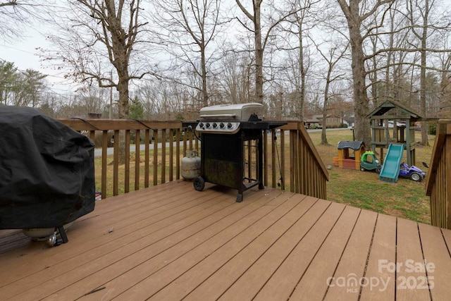 wooden terrace featuring a playground, a grill, and a lawn