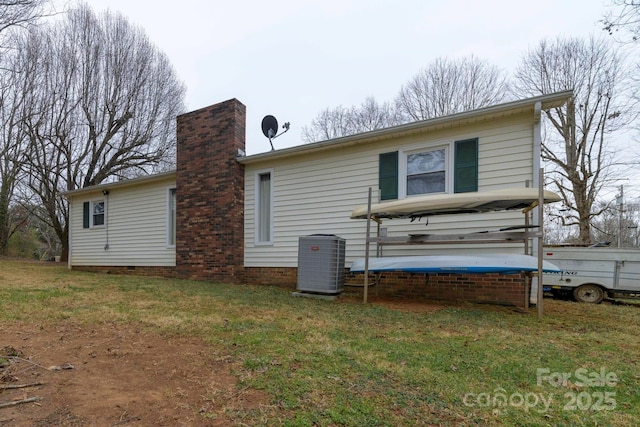 rear view of property with a yard, central AC unit, a chimney, and crawl space