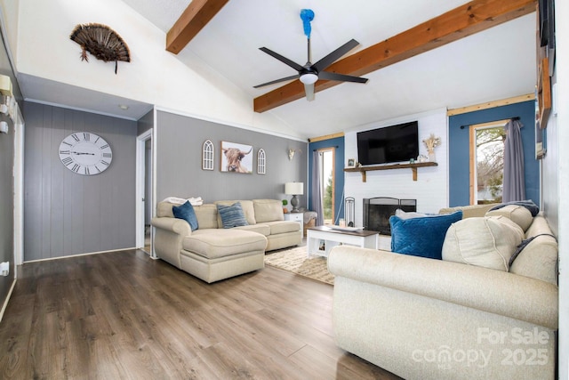 living area featuring beam ceiling, a large fireplace, ceiling fan, wood finished floors, and high vaulted ceiling