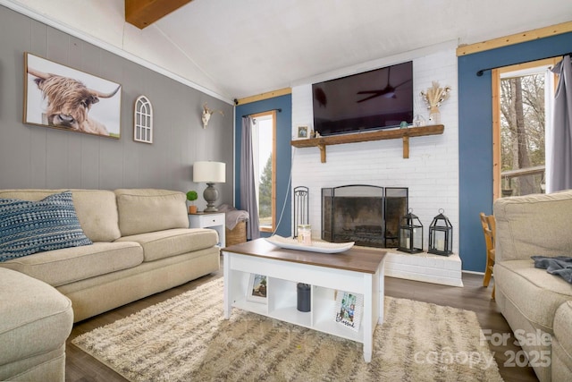 living room featuring a fireplace, vaulted ceiling with beams, and wood finished floors