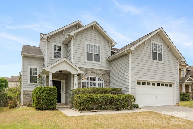 traditional-style house with stone siding, an attached garage, concrete driveway, and a front yard