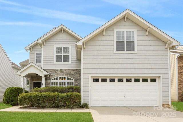 view of front of property featuring concrete driveway, stone siding, and a garage