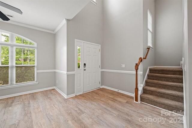 foyer entrance with a ceiling fan, wood finished floors, stairway, baseboards, and crown molding