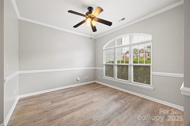 spare room with wood finished floors, ceiling fan, baseboards, and crown molding