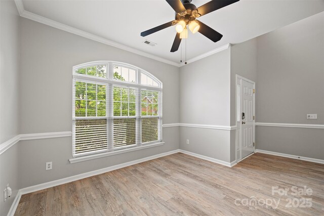 spare room with baseboards, light wood-style flooring, crown molding, and a ceiling fan