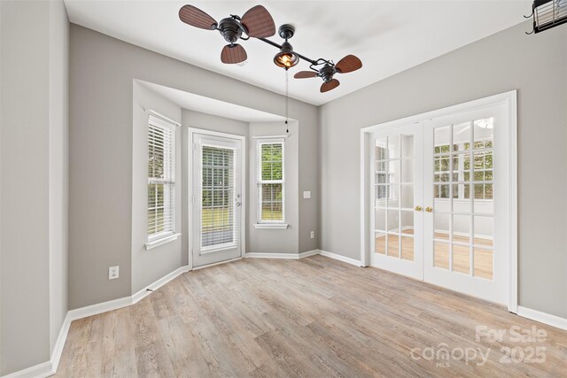 empty room with french doors, wood finished floors, baseboards, and plenty of natural light