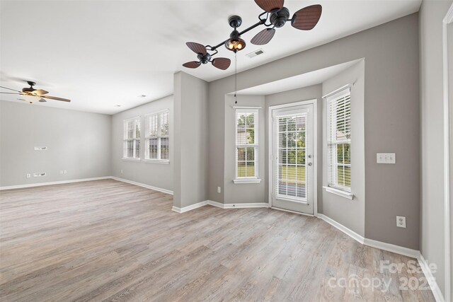 spare room featuring ceiling fan, light wood-type flooring, and baseboards