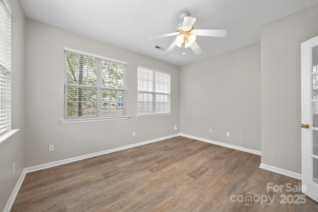 spare room featuring wood finished floors, baseboards, and a ceiling fan