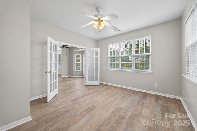spare room featuring french doors, ceiling fan, baseboards, and wood finished floors