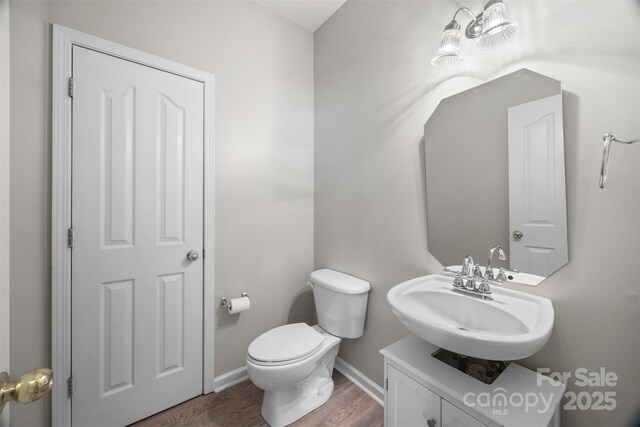 bathroom with wood finished floors, baseboards, toilet, and vanity