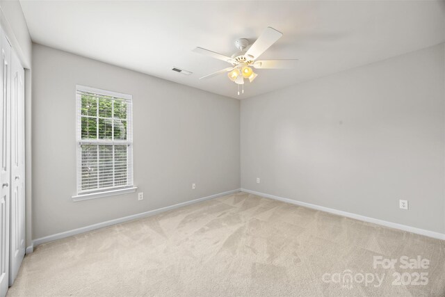 spare room featuring light colored carpet, baseboards, and a ceiling fan