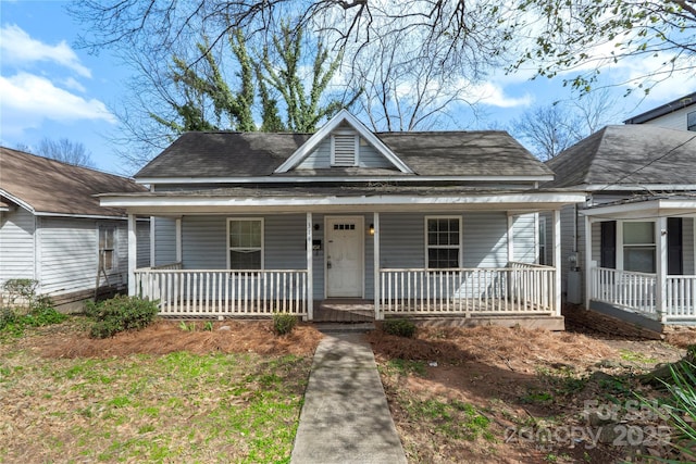 bungalow featuring a porch and roof with shingles