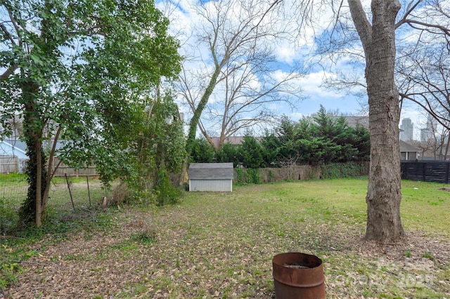 view of yard featuring a storage shed, fence, and an outdoor structure