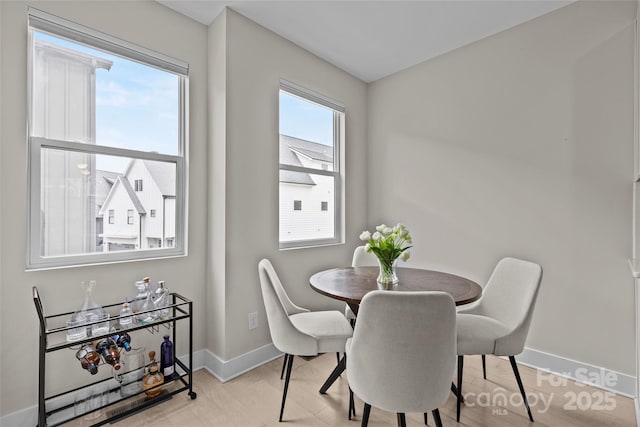 dining area with a wealth of natural light, light wood-style floors, and baseboards