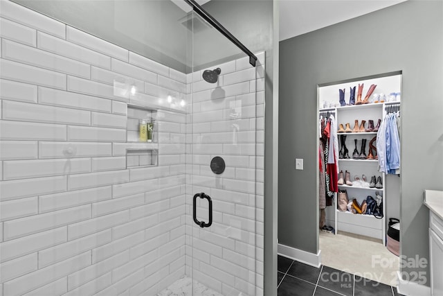 full bathroom with a spacious closet, baseboards, a stall shower, tile patterned floors, and vanity