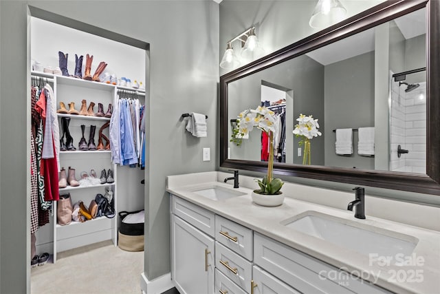 full bath with double vanity, a spacious closet, a shower, and a sink