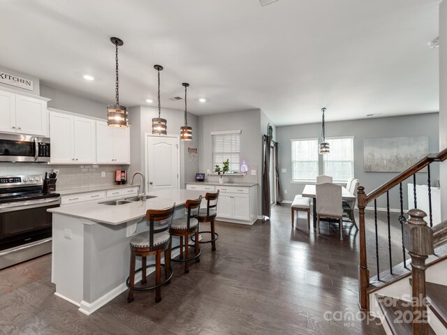 kitchen featuring a breakfast bar area, a sink, stainless steel appliances, light countertops, and backsplash