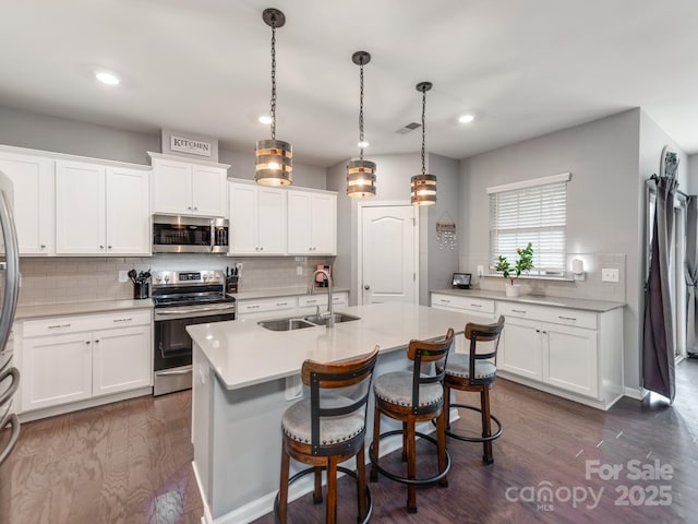 kitchen featuring white cabinets, appliances with stainless steel finishes, light countertops, and a sink