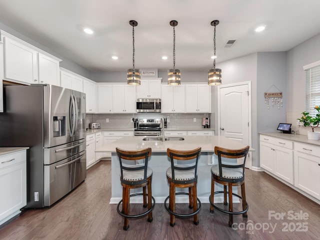 kitchen with dark wood finished floors, light countertops, visible vents, appliances with stainless steel finishes, and a sink