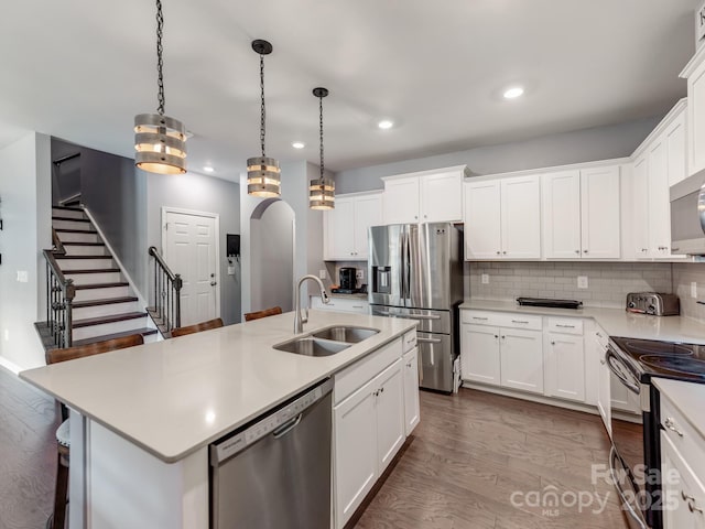 kitchen featuring tasteful backsplash, appliances with stainless steel finishes, arched walkways, and a sink