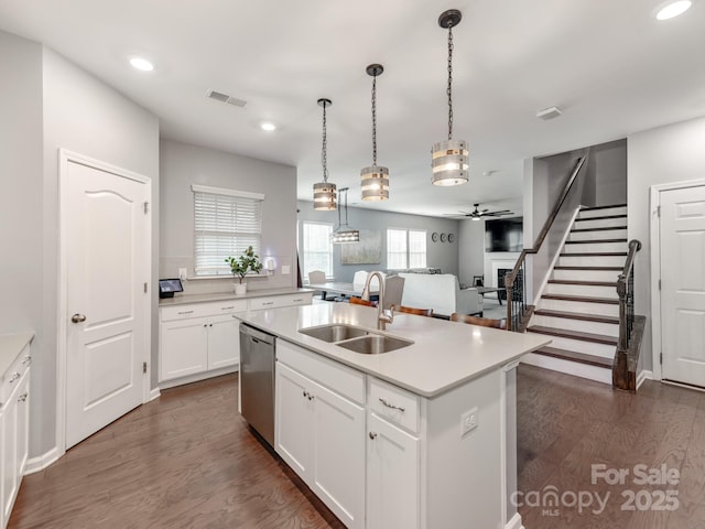 kitchen with a sink, visible vents, light countertops, stainless steel dishwasher, and dark wood finished floors