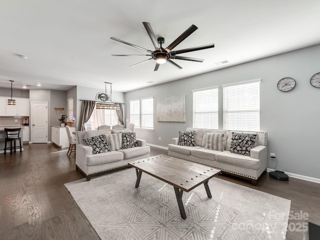 living area featuring dark wood-style floors, a ceiling fan, visible vents, and baseboards