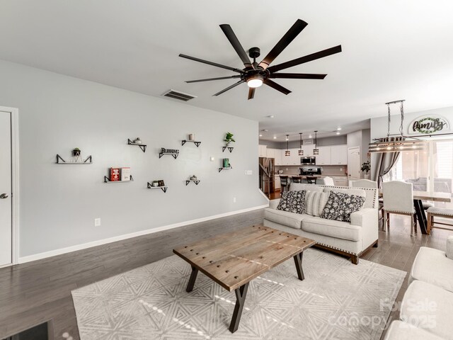 living room featuring stairs, wood finished floors, visible vents, and baseboards