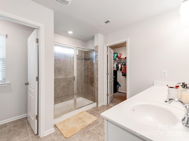 full bathroom with a sink, visible vents, a shower stall, tile patterned floors, and a walk in closet