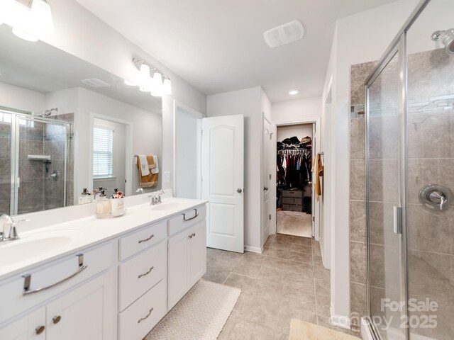 bathroom featuring double vanity, a stall shower, a sink, and a walk in closet