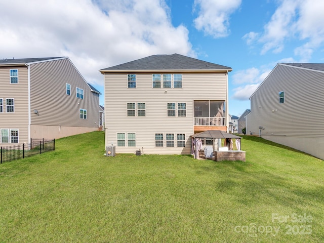 back of property featuring a gazebo, a lawn, fence, and a sunroom