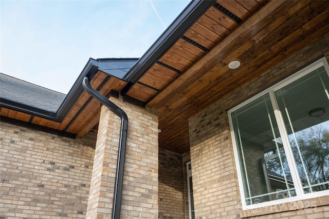 view of side of home featuring covered porch and brick siding