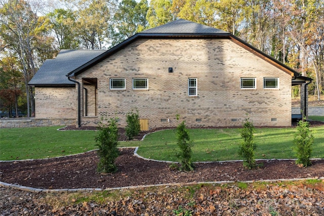 view of property exterior with crawl space, brick siding, and a lawn