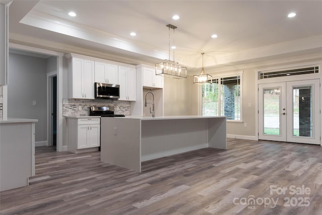 kitchen with white cabinets, stainless steel appliances, and a raised ceiling