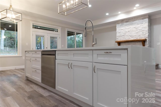 kitchen with white cabinetry, light wood-style flooring, ornamental molding, and a wealth of natural light