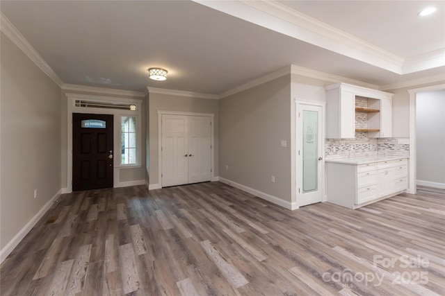 entryway with baseboards, wood finished floors, and ornamental molding