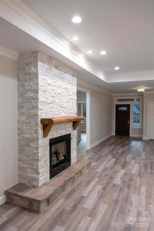 unfurnished living room with baseboards, a fireplace, ornamental molding, and wood finished floors