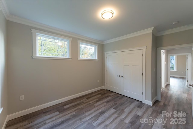 unfurnished bedroom with ornamental molding, wood finished floors, and baseboards