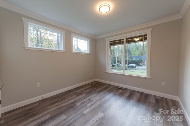 empty room with dark wood-style floors, baseboards, and crown molding