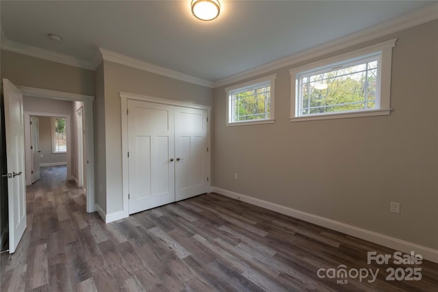 unfurnished bedroom featuring ornamental molding, a closet, baseboards, and wood finished floors