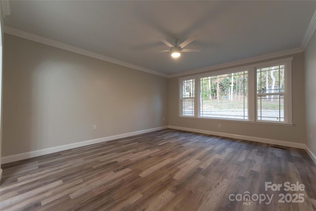 empty room featuring ornamental molding, dark wood-type flooring, and baseboards