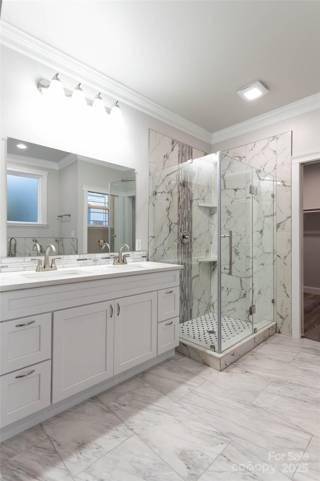 full bath featuring ornamental molding, a sink, a marble finish shower, and double vanity