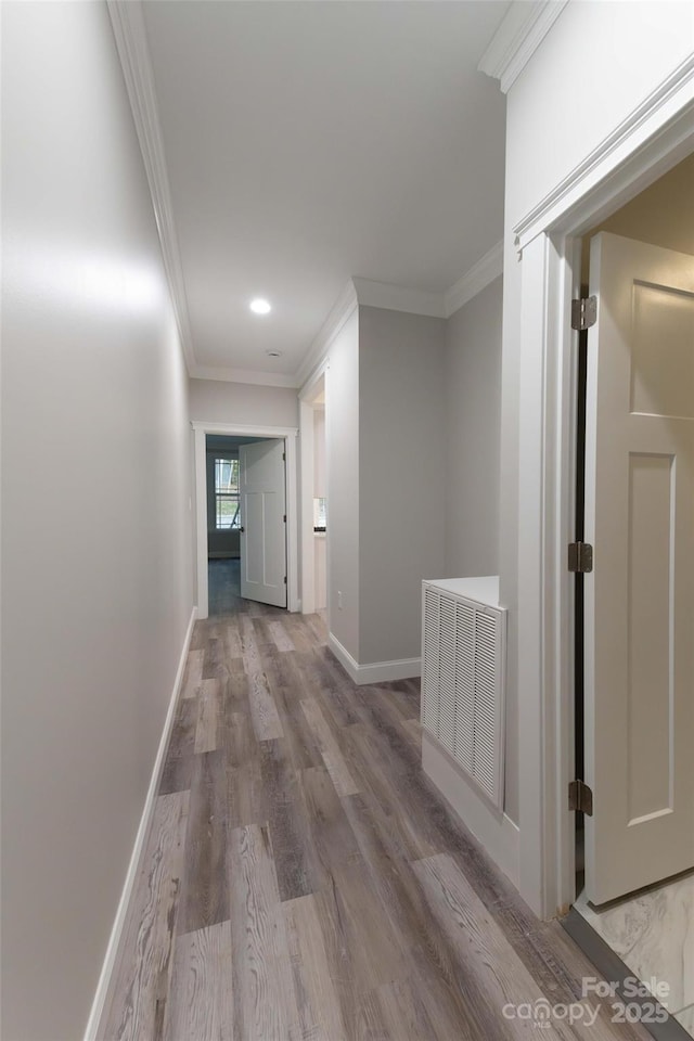 hallway featuring ornamental molding, visible vents, and baseboards