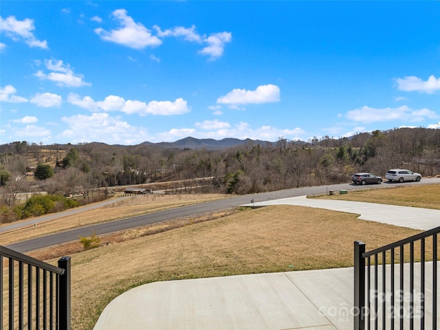 view of yard featuring fence, a mountain view, and a wooded view