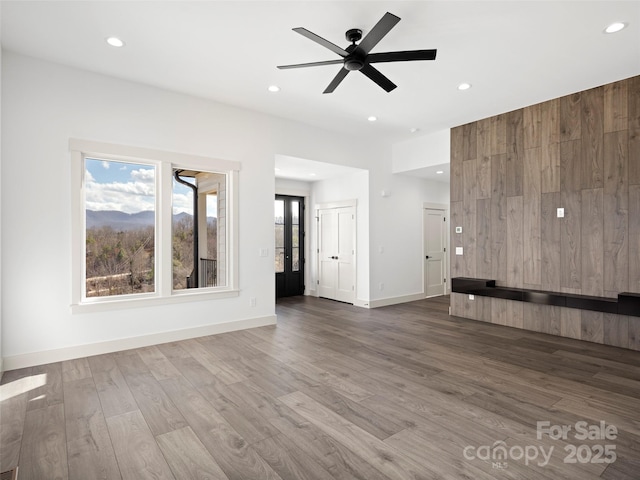 unfurnished living room with recessed lighting, ceiling fan, baseboards, and wood finished floors