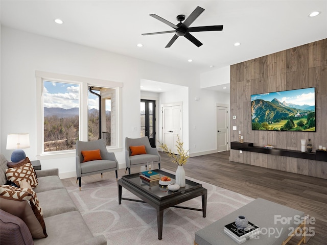 living room with baseboards, ceiling fan, wood finished floors, wood walls, and recessed lighting